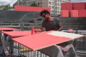 Handwerker streicht Holzplatte rot an